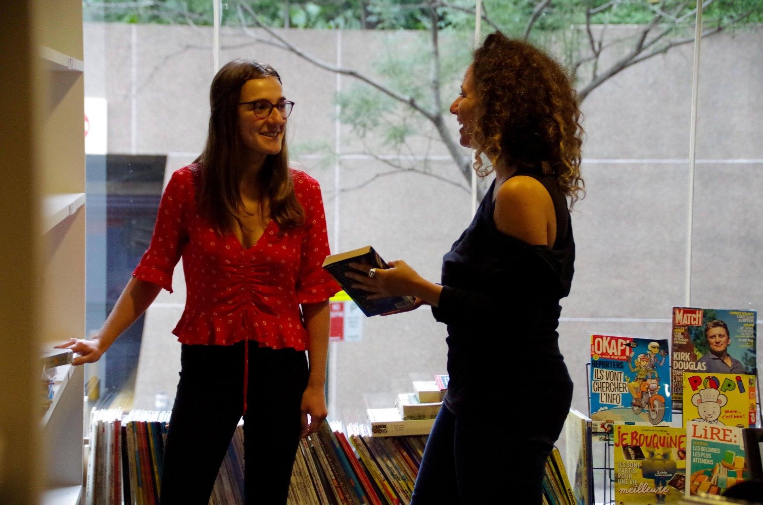 Two women smiling together in the French library at Alliance Francaise de Sydney